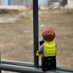 Lego-Fotograf steht am Zaun zur Baustelle